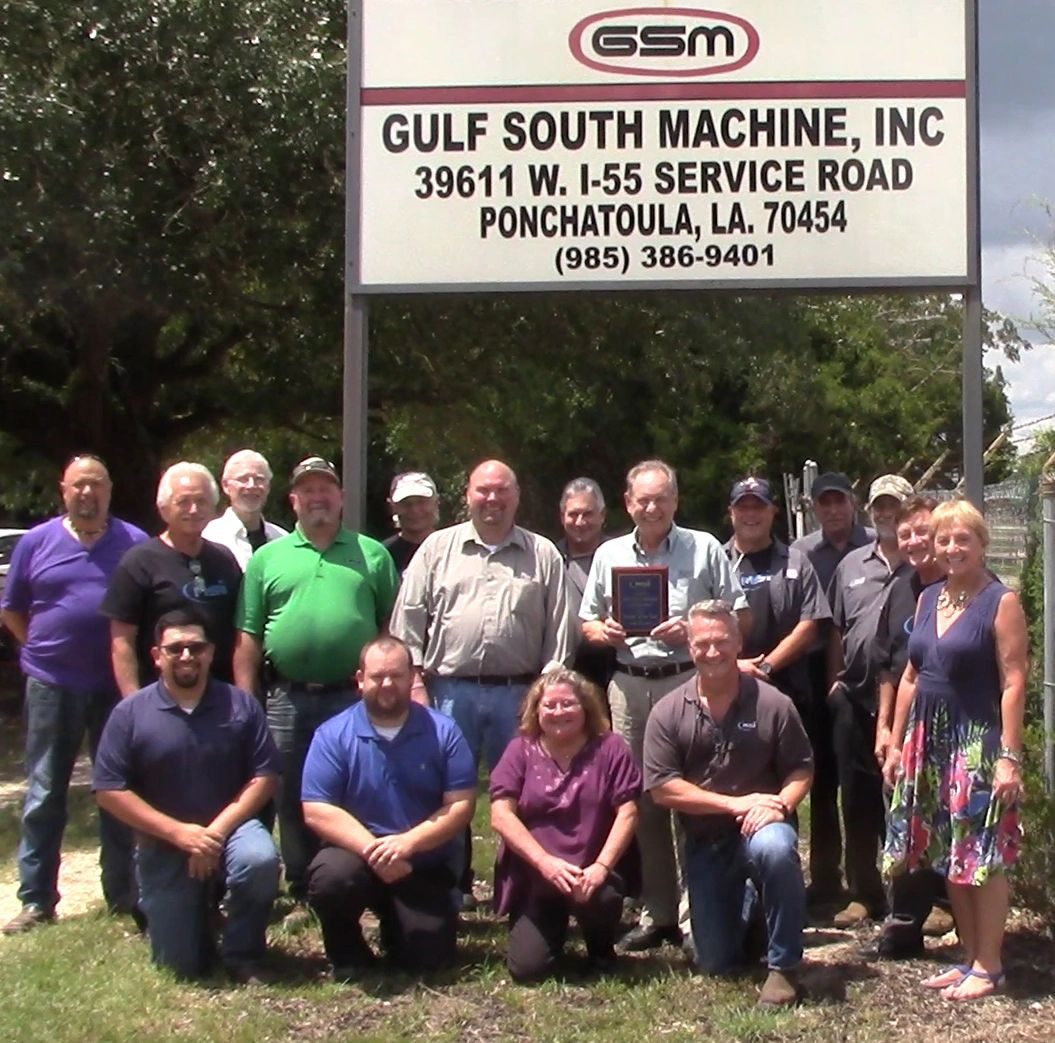 The Gulf South Machine team in front of the GSM sign